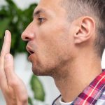 A man checking his breath with his hand